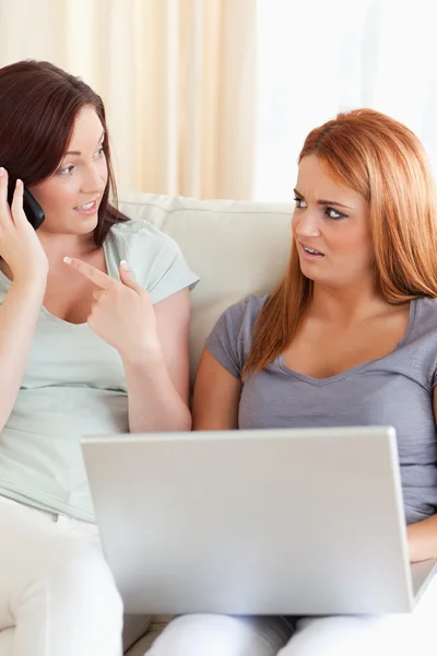 Upset Women sitting on a sofa with a laptop and a phone — Stock Photo, Image