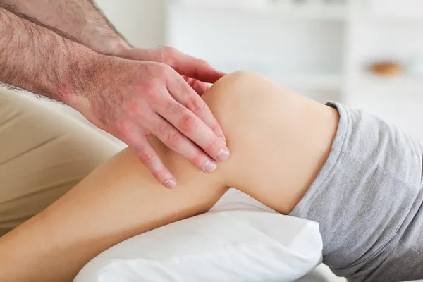 Man masseren een liegen vrouw knie — Stockfoto