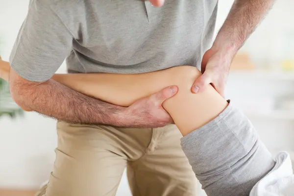 Chiropractor massaging a patient's knee — Stock Photo, Image