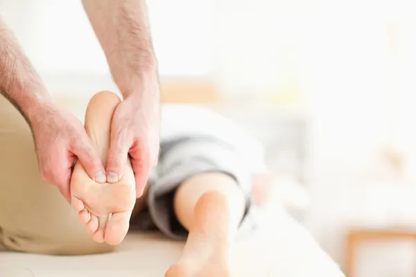 Мужской массажист массирует женские ноги — стоковое фото