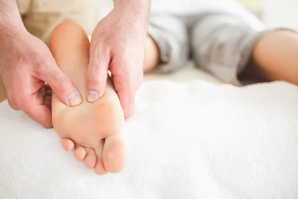 Mannelijke masseur, een vrouw voet masseren — Stockfoto