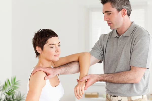 Quiropráctico estirando el brazo de una mujer —  Fotos de Stock
