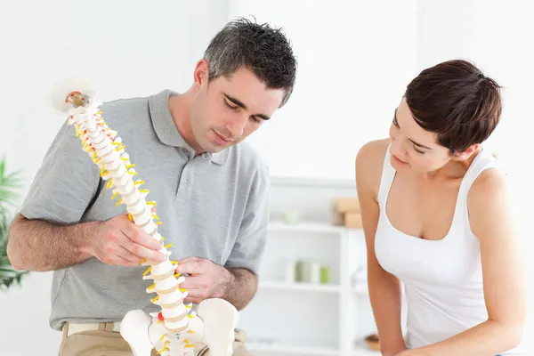 Quiroprático e paciente olhando para um modelo de coluna vertebral — Fotografia de Stock