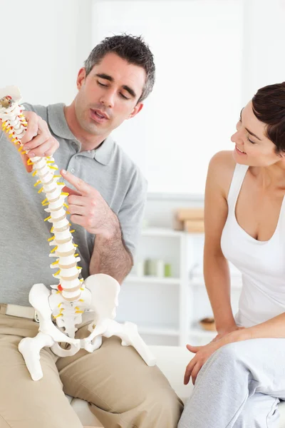 Quiropráctico explicando la columna vertebral a una mujer — Foto de Stock