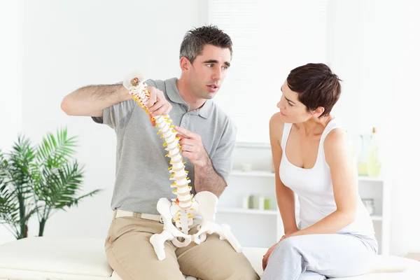 Morena mulher olhando para um modelo-coluna vertebral — Fotografia de Stock