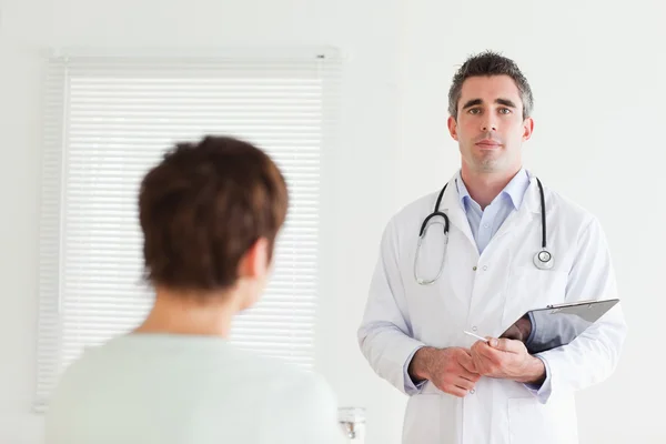 Серйозний лікар розмовляє з брюнеткою — стокове фото