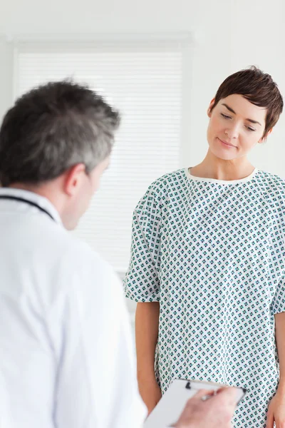 Femme en robe d'hôpital parlant à son médecin — Photo