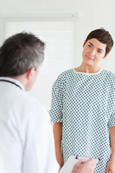 Cute Woman in hospital gown talking to her doctor — Stock Photo, Image
