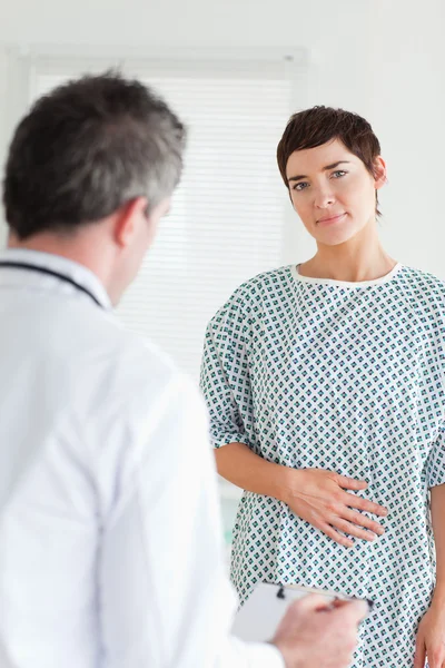Uroczy kobieta w sukni szpitala rozmawia z jej lekarzem — Zdjęcie stockowe