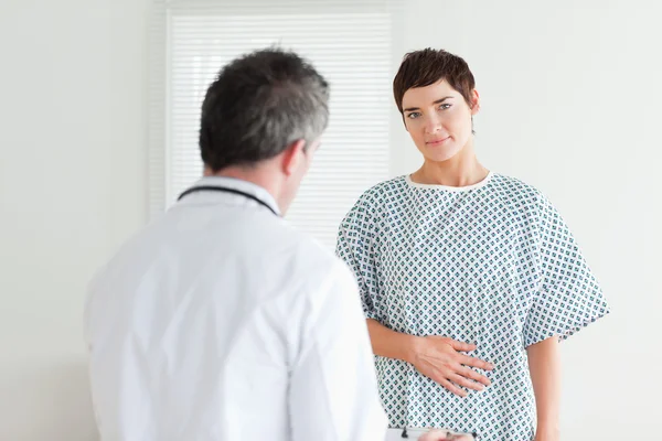 Brünette Frau im Krankenhauskleid im Gespräch mit ihrem Arzt — Stockfoto