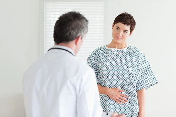 Молода жінка в лікарняній сукні розмовляє зі своїм лікарем — стокове фото