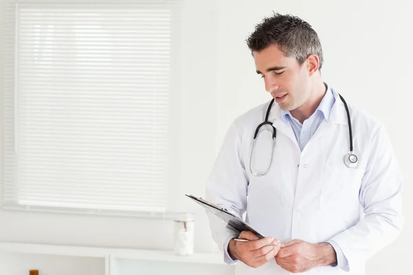 Smiling male Doctor looking at a chart — Stock Photo, Image
