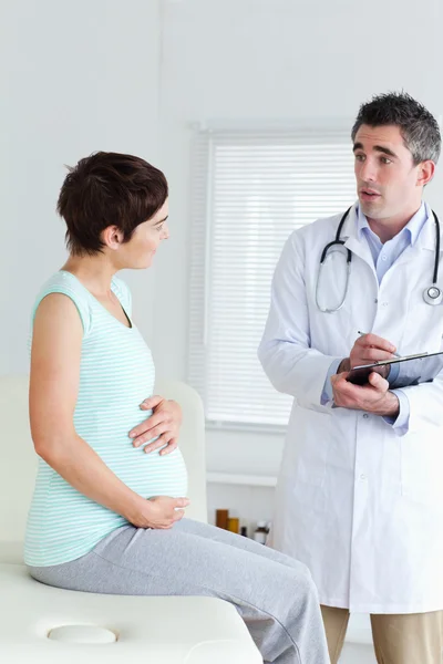 Сидящая беременная женщина разговаривает со своим врачом — стоковое фото