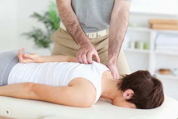 Massagista massageando o ombro de uma mulher morena — Fotografia de Stock