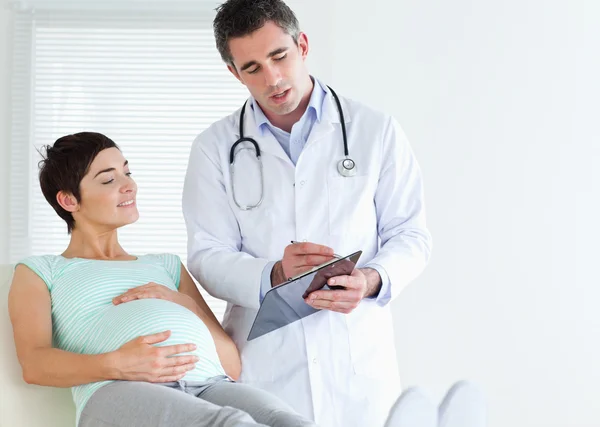 Femme enceinte couchée parlant à son médecin — Photo