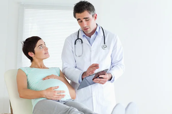 妊娠中の女性に何かを説明する医者 — ストック写真