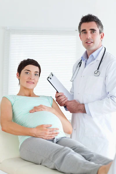 Lekarz i pacjent ciąży patrząc na kamery — Zdjęcie stockowe