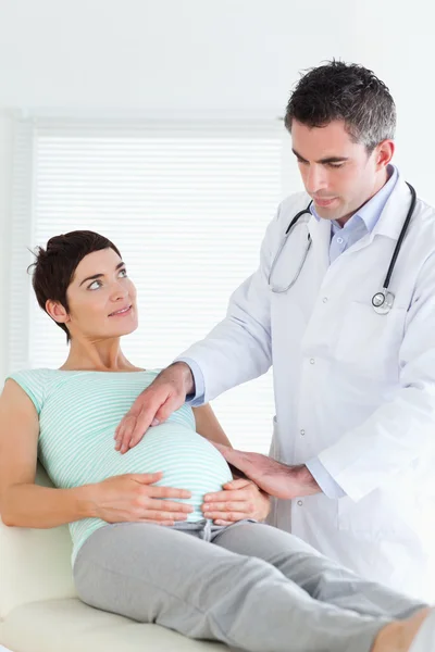 Läkare undersöka en gravid kvinnas mage — Stockfoto