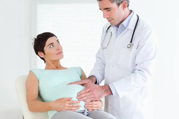 Lekarz ausculating kobiety w ciąży brzuch — Zdjęcie stockowe