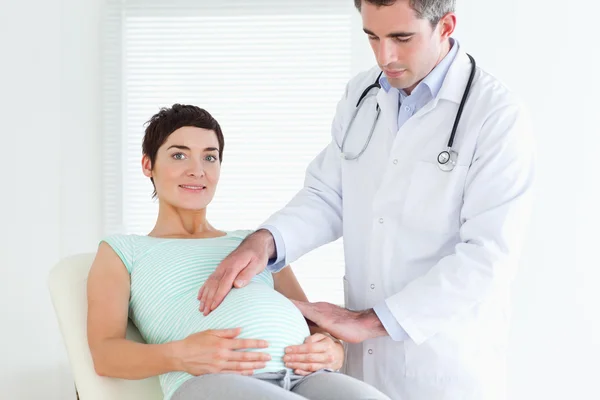 Médico masculino auscultando a barriga de uma mulher grávida — Fotografia de Stock