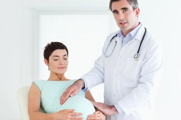 Maschio medico esaminando pancia di una donna incinta — Foto Stock