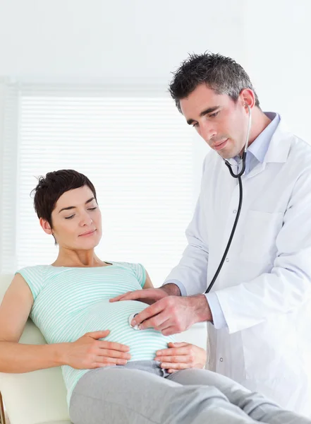 Doctor escuchando en el vientre con un estetoscopio —  Fotos de Stock