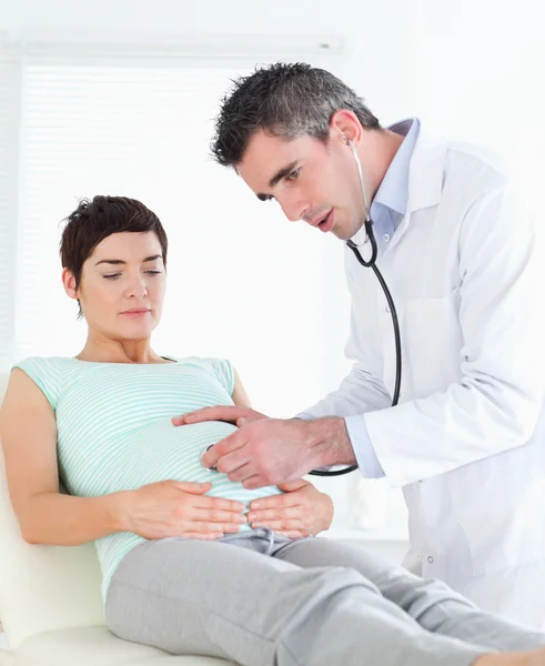 Doktor poslech do ženské břicho se stetoskopem — Stock fotografie