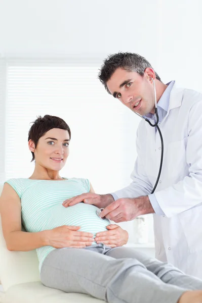 Γιατρός εξετάζει μια έγκυος γυναίκα με ένα στηθοσκόπιο — Φωτογραφία Αρχείου