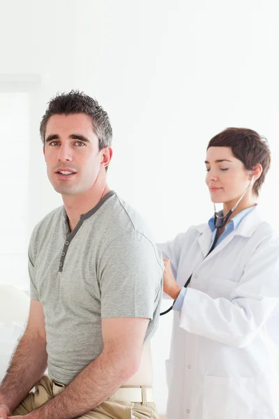 Läkaren undersöker en patient med stetoskop — Stockfoto