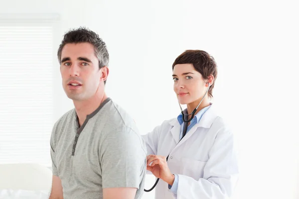 Charming Doctor esamina un paziente con uno stetoscopio — Foto Stock