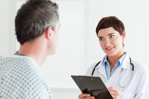 Läkare pratar med en manlig patient som innehar ett diagram — Stockfoto