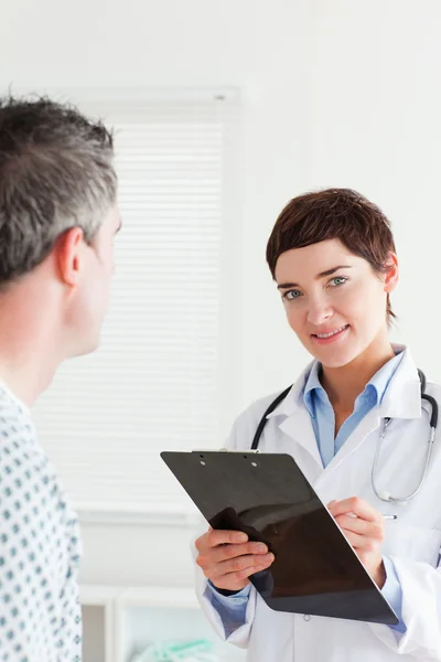 Médico falando com um paciente do sexo masculino enquanto segurando um gráfico — Fotografia de Stock