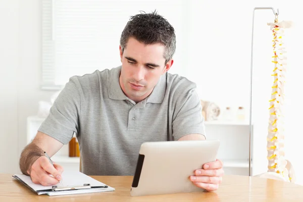 男子坐在一张桌子与平板电脑和图表 — 图库照片