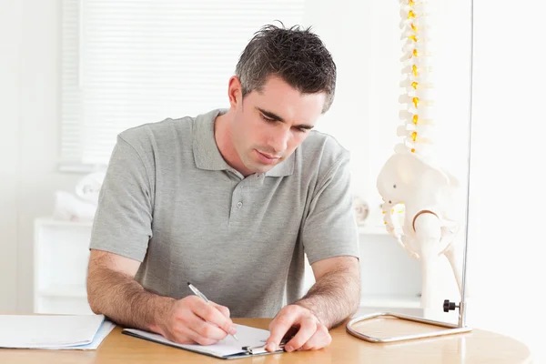 Male Doctor sitting at a table working — Stock Photo, Image