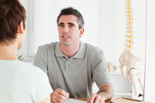 Doctor and patient sitting at a table talking — Stock Photo, Image