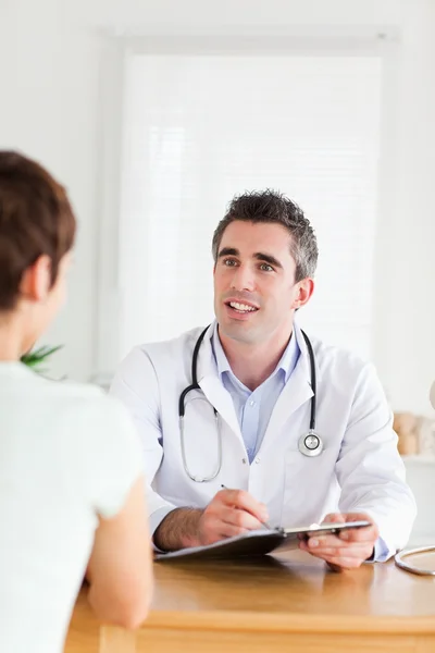 Uśmiechający się lekarz mówi do pacjenta brunetka — Zdjęcie stockowe