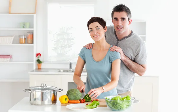 Муж массирует жену, пока она режет овощи. — стоковое фото