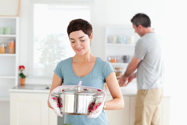 Roztomilá žena držící hrnec, zatímco muž je mytí nádobí — Stock fotografie