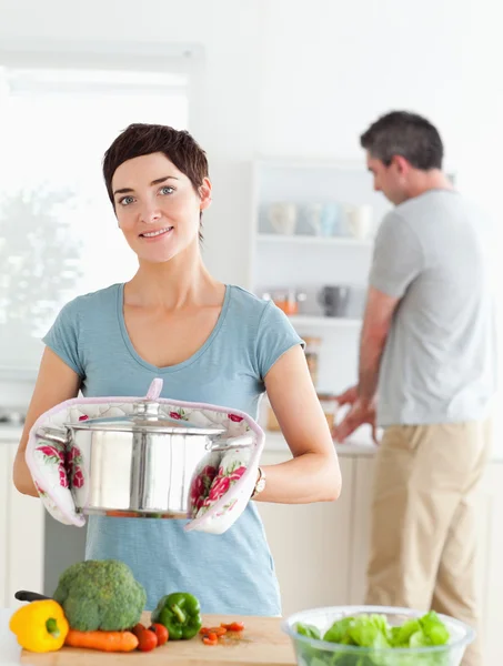 Очаровательная жена держит кастрюлю, пока ее муж моет посуду — стоковое фото