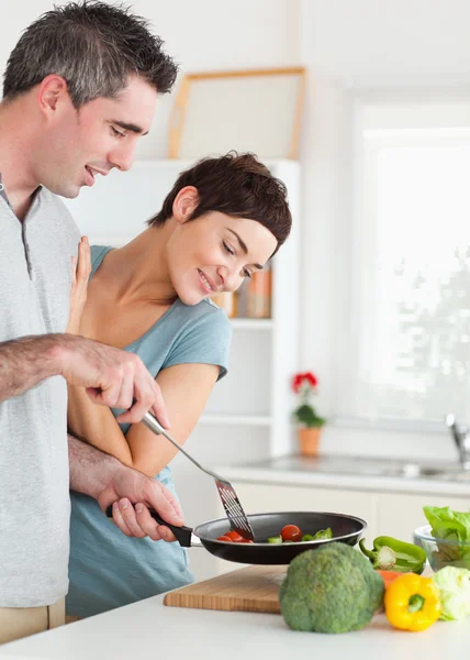 Чарівна жінка, дивлячись на сковороду її чоловік тримає — стокове фото