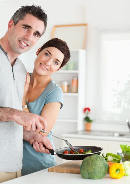 Gorgeous Woman and her pan-holding husband looking into the came — Stock Photo, Image