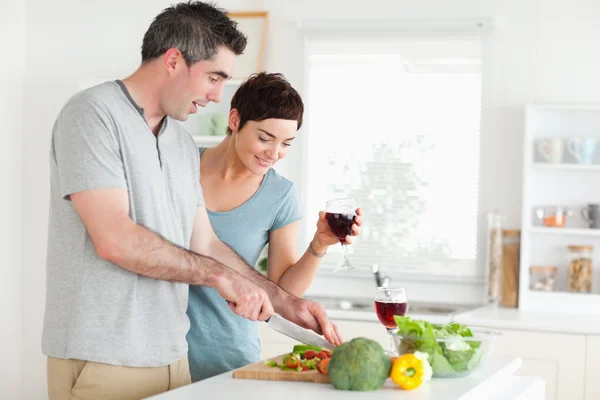 Uomo tagliare le verdure mentre è donna sta guardando — Foto Stock