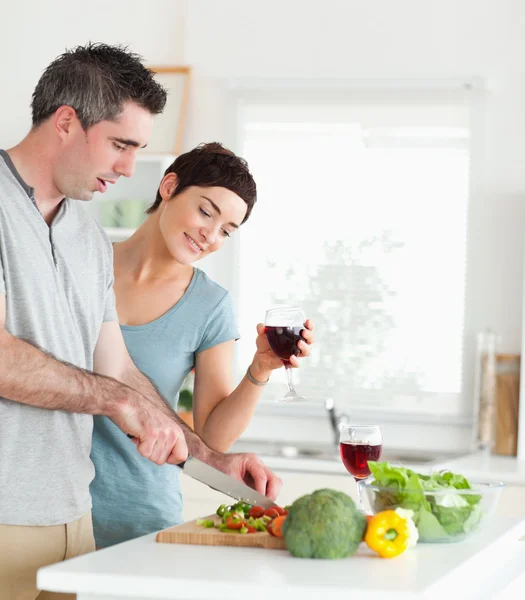 Pohledný muž, řezání zeleniny přitom je, že žena se dívá — Stock fotografie