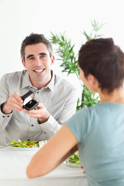 Glimlachende man stelt zijn verrast vriendin tijdens het diner — Stockfoto