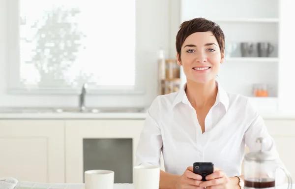 Vrouw met telefoon en koffie op zoek naar camera — Stockfoto