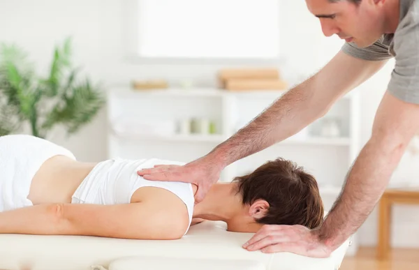 En massör massera en kvinnas rygg — Stockfoto