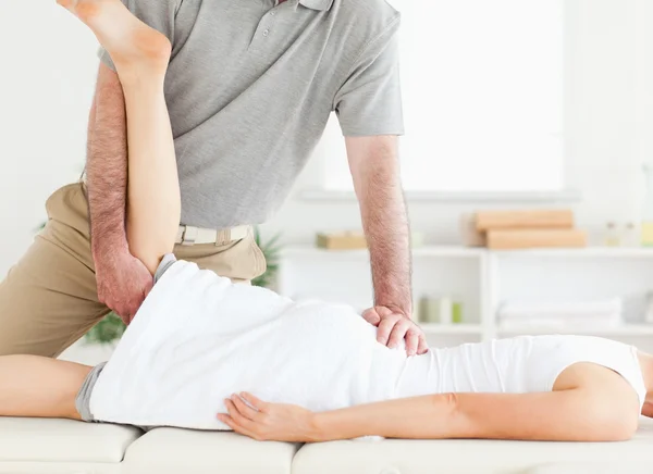 Chiropractor is een vrouw been uitrekkende — Stockfoto