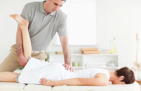 A chiropractor stretches a customer's leg — Stock Photo, Image