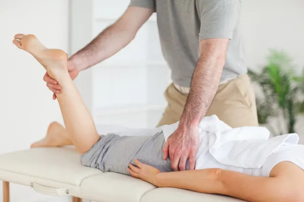 Chiropractor strekt zich uit van een vrouwelijke klant been — Stockfoto