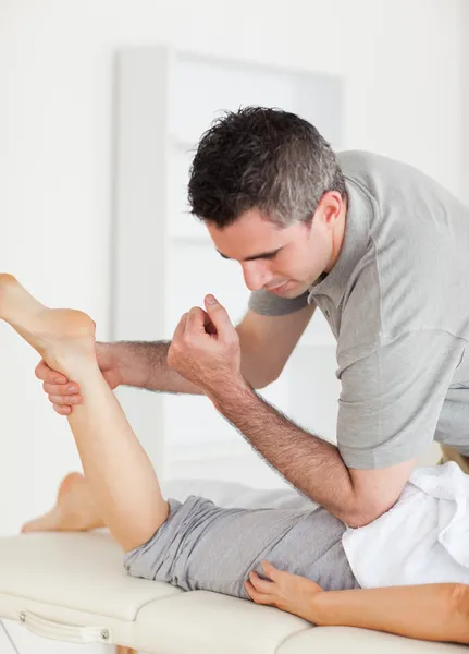 Kiropraktor sträcker sig kvinnliga kundens ben — Stockfoto